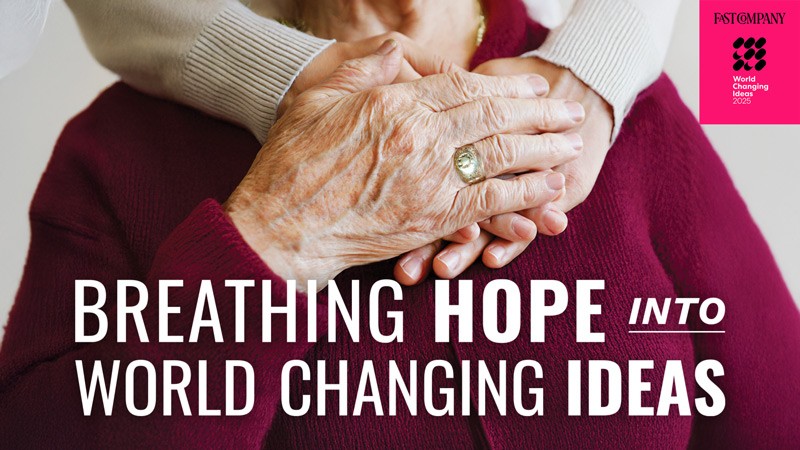 An elderly woman's hands grasp a younger person's hands beneath the words "Breathing Hope into World Changing Ideas"