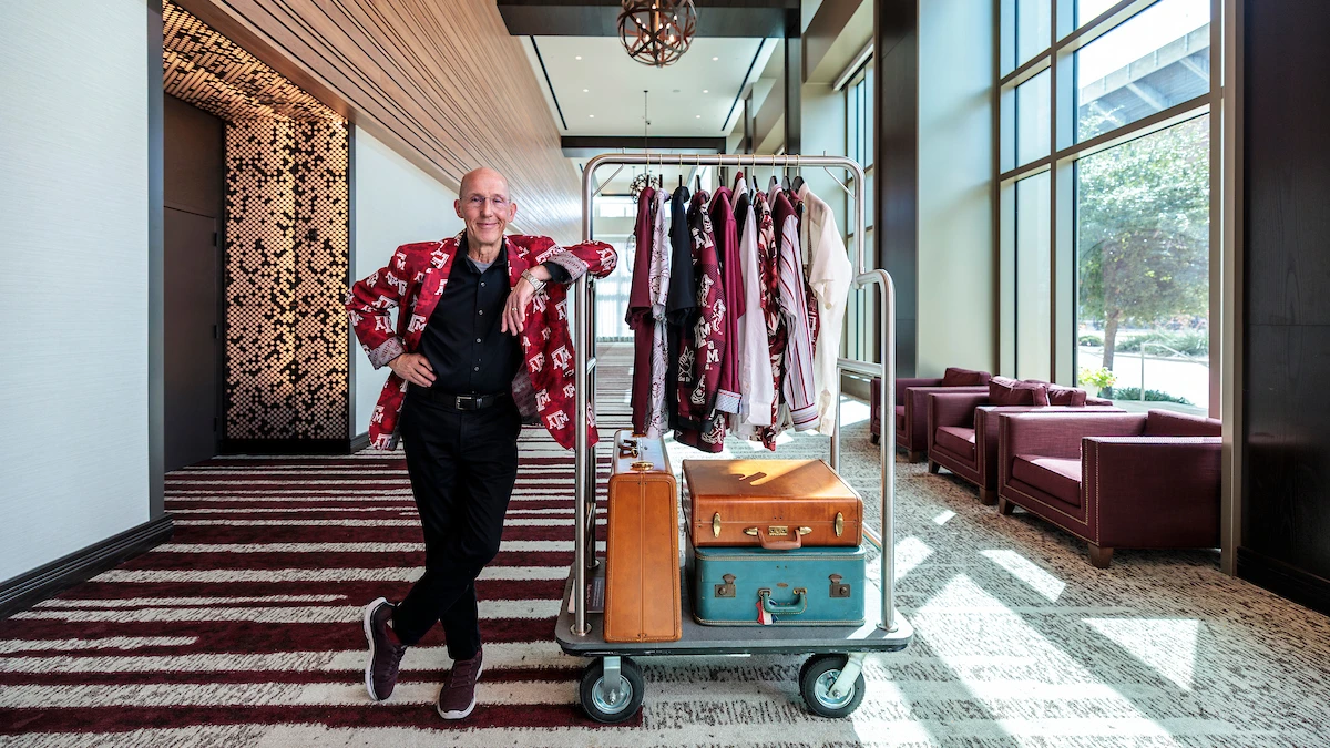 Portrait of Sean Artman, Texas A&M Hotel doorman, posing with a full luggage cart