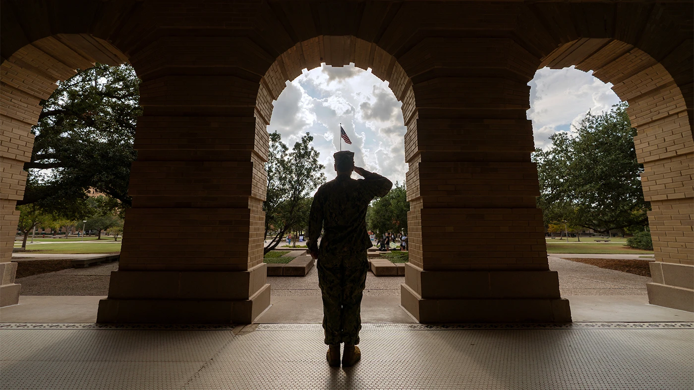 A silhouette of a veteran saluting an American flag on the Texas A&M campus