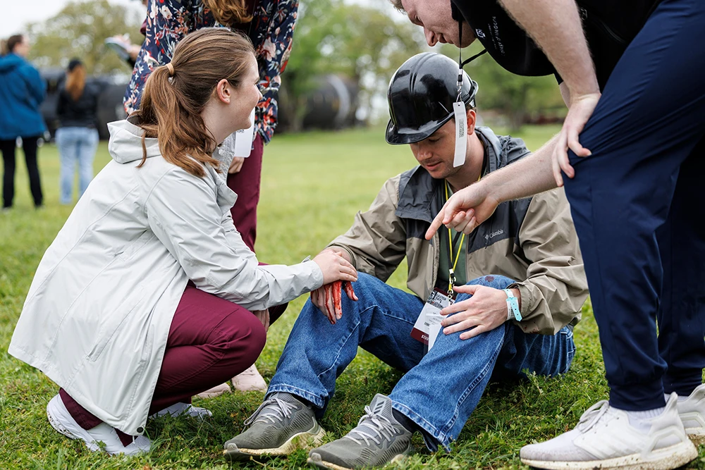 Nursing students assist Disaster Day participant with a hardhat on