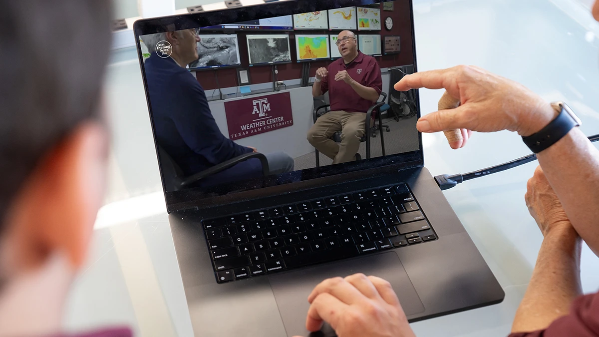 Two people watch a Texas A&M expert on a laptop